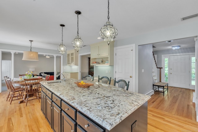 16 Cider Mill Rd, Burlington, CT 06013 - kitchen with light wood-type flooring, a baseboard heating unit, hanging light fixtures, light stone countertops, and a center island with sink