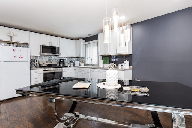 kitchen with appliances with stainless steel finishes, decorative backsplash, a sink, and white cabinetry