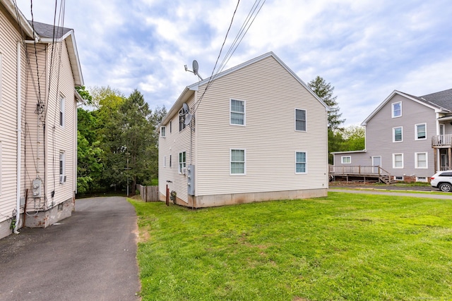 view of side of property featuring a yard and asphalt driveway