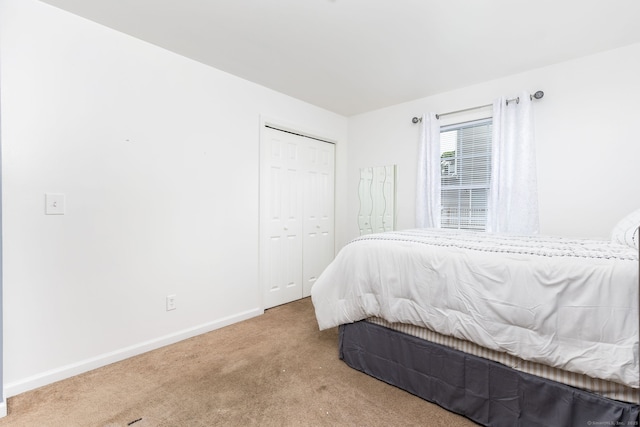 carpeted bedroom with baseboards and a closet