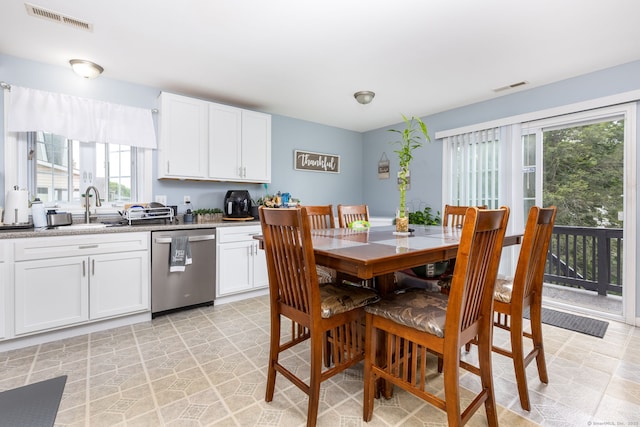 kitchen featuring dishwasher, a sink, healthy amount of natural light, and white cabinets
