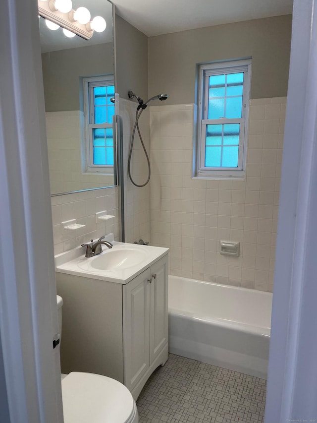bathroom featuring tile walls, tile patterned floors, toilet, vanity, and bathtub / shower combination
