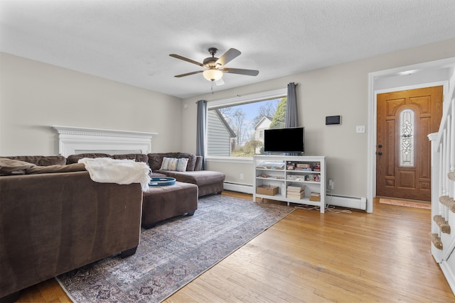 living room featuring a ceiling fan, a baseboard heating unit, hardwood / wood-style flooring, a baseboard radiator, and a textured ceiling