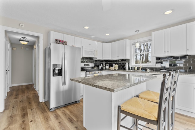 kitchen with appliances with stainless steel finishes, tasteful backsplash, white cabinetry, a kitchen island, and recessed lighting