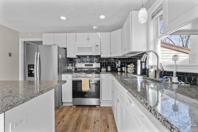 kitchen with appliances with stainless steel finishes, a sink, white cabinets, tasteful backsplash, and recessed lighting