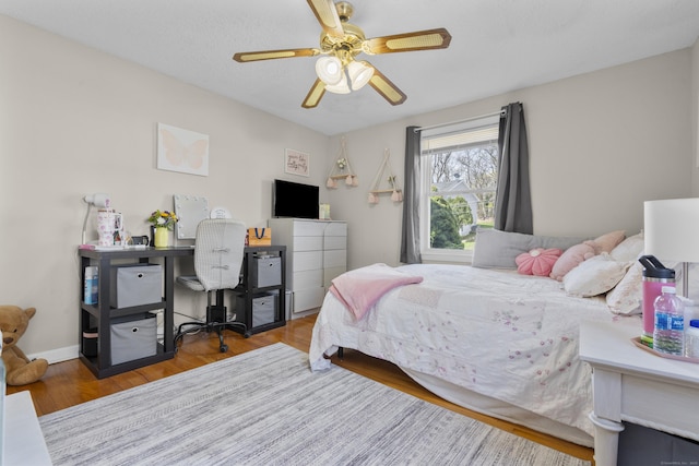 bedroom with a desk, wood finished floors, and a ceiling fan