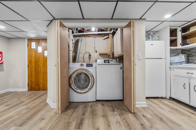 laundry area featuring washing machine and dryer, light wood-type flooring, and baseboards