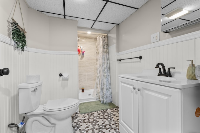 bathroom with a wainscoted wall, toilet, a shower stall, tile patterned floors, and vanity