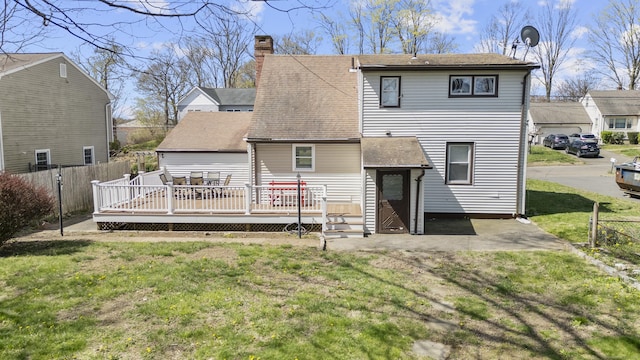 rear view of house with a deck, a chimney, and roof with shingles
