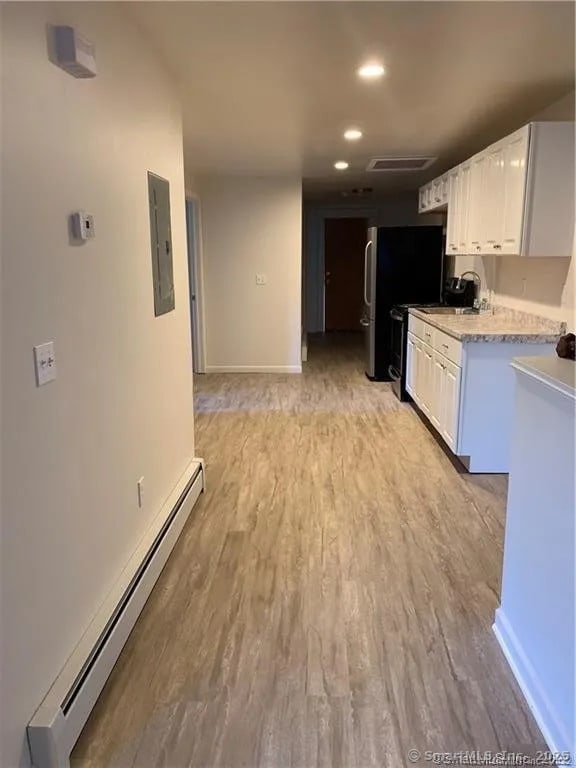 15 Townley St, Hartford, CT 06105 - kitchen featuring a baseboard heating unit, electric panel, white cabinets, light countertops, and light wood-style floors