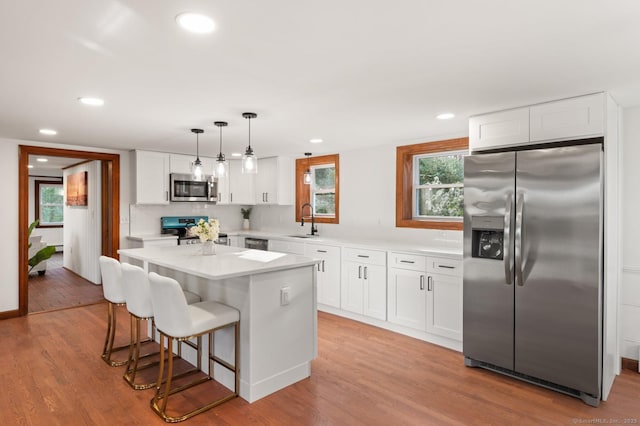 689 S Meriden Rd, Cheshire, CT 06410 - kitchen with stainless steel appliances, a sink, a breakfast bar area, white cabinets, and light wood-style flooring