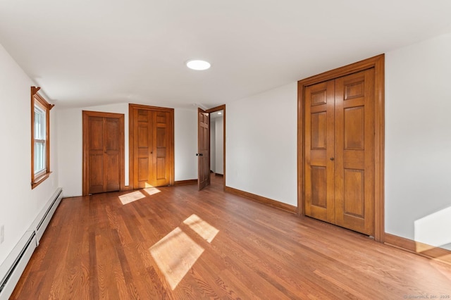 689 S Meriden Rd, Cheshire, CT 06410 - unfurnished bedroom with a baseboard heating unit, wood finished floors, two closets, and baseboards