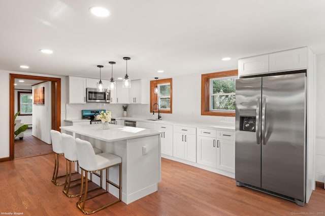 689 S Meriden Rd, Cheshire, CT 06410 - kitchen with appliances with stainless steel finishes, a sink, a kitchen bar, white cabinetry, and light wood-style flooring