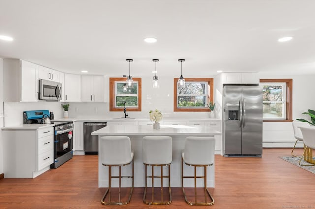 689 S Meriden Rd, Cheshire, CT 06410 - kitchen featuring appliances with stainless steel finishes, a baseboard heating unit, a breakfast bar area, light wood-style flooring, and recessed lighting