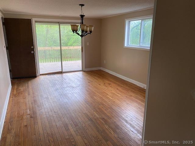 147 Chester St, East Hartford, CT 06108 - unfurnished dining area featuring a chandelier, hardwood / wood-style floors, baseboards, and crown molding
