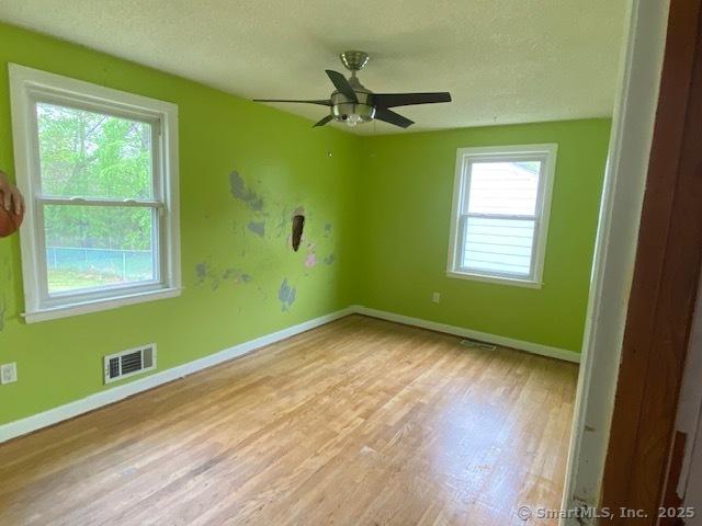 147 Chester St, East Hartford, CT 06108 - empty room with wood finished floors, healthy amount of natural light, a textured ceiling, baseboards, and a ceiling fan