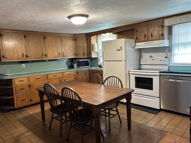 2060 Perkins St, Bristol, CT 06010 - kitchen featuring stainless steel appliances, under cabinet range hood, a textured ceiling, brown cabinetry, and dark tile patterned floors