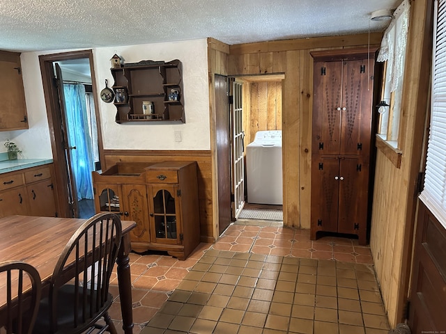 2060 Perkins St, Bristol, CT 06010 - kitchen featuring washer / clothes dryer, a textured ceiling, wood walls, light tile patterned flooring, and light countertops