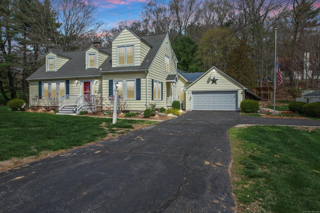 cape cod house with an outbuilding, a front yard, and asphalt driveway
