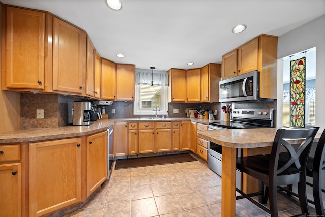kitchen with appliances with stainless steel finishes, decorative backsplash, a sink, light tile patterned floors, and recessed lighting