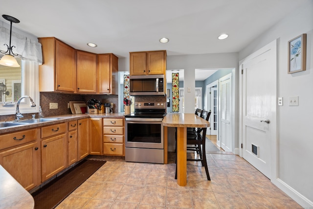 kitchen with stainless steel appliances, a sink, tasteful backsplash, brown cabinets, and pendant lighting