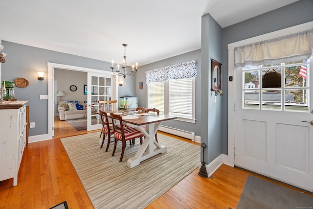 dining area featuring a chandelier, a baseboard radiator, light wood-type flooring, and baseboards