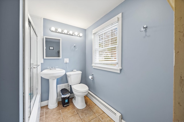 bathroom featuring a baseboard radiator, toilet, baseboards, tile patterned floors, and a sink