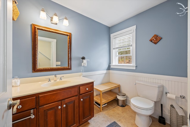 bathroom featuring a wainscoted wall, vanity, toilet, and tile patterned flooring