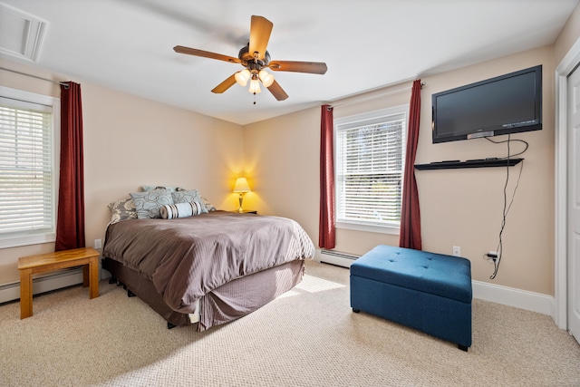 carpeted bedroom featuring baseboard heating, multiple windows, and a ceiling fan