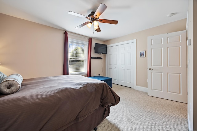 bedroom with light carpet, a closet, ceiling fan, and baseboards