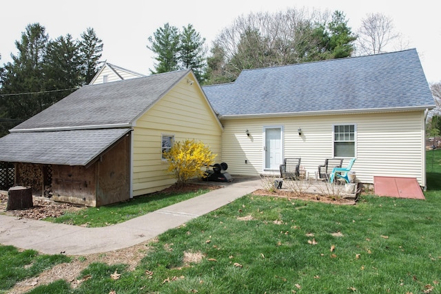 back of house with a yard, a shingled roof, and a patio area