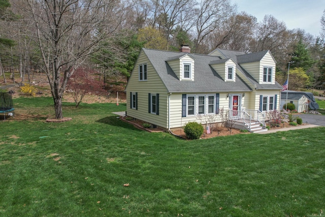 view of front of property with a trampoline, a chimney, roof with shingles, and a front lawn