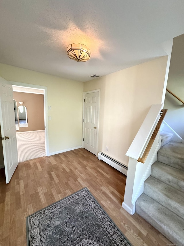 26 John George Dr, Meriden, CT 06450 - entryway with a baseboard heating unit, wood finished floors, baseboards, stairs, and a textured ceiling