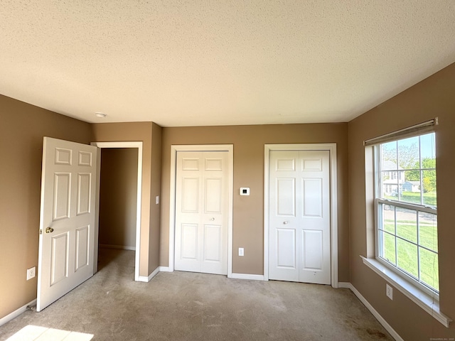 26 John George Dr, Meriden, CT 06450 - unfurnished bedroom with multiple windows, multiple closets, a textured ceiling, and carpet floors