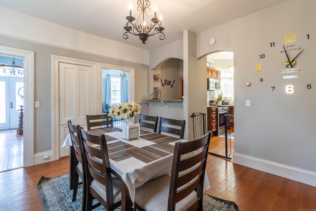 61 Williams St, Norwich, CT 06360 - dining area with a chandelier, arched walkways, baseboards, and wood finished floors