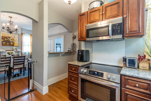 61 Williams St, Norwich, CT 06360 - kitchen featuring appliances with stainless steel finishes, arched walkways, light wood-type flooring, light stone counters, and vaulted ceiling