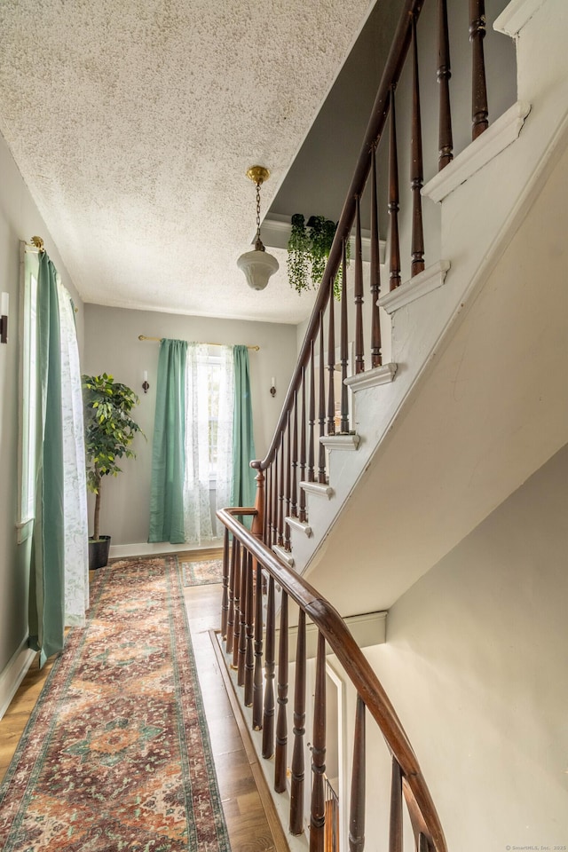 61 Williams St, Norwich, CT 06360 - stairway featuring a textured ceiling, wood finished floors, and baseboards