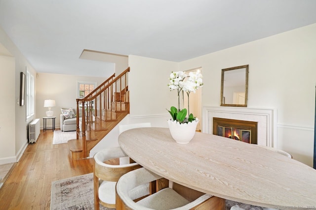 8 Bailey St, Trumbull, CT 06611 - dining area featuring radiator heating unit, stairs, light wood-style flooring, and a glass covered fireplace
