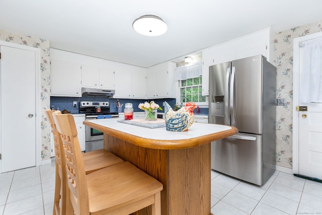 1 Meadowview Ln, Bloomfield, CT 06002 - kitchen with stainless steel appliances, wallpapered walls, under cabinet range hood, light tile patterned floors, and a center island