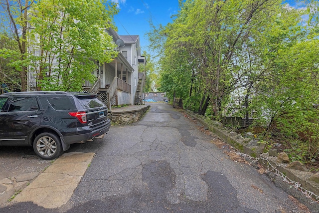 view of side of property featuring stairway and asphalt driveway