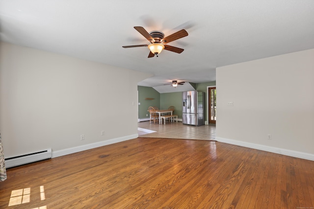 spare room featuring baseboard heating, ceiling fan, baseboards, and wood finished floors