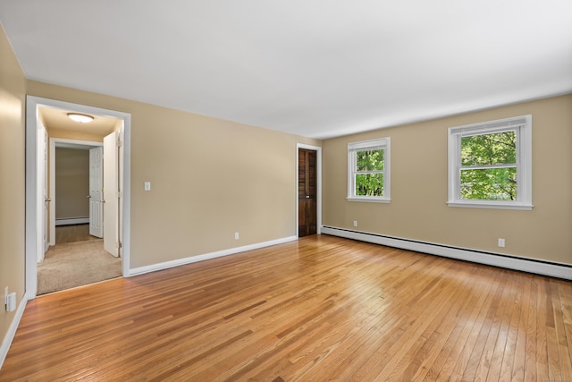 spare room with a baseboard radiator, light wood finished floors, baseboard heating, and baseboards