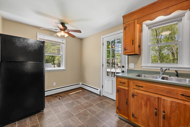 kitchen featuring freestanding refrigerator, a sink, healthy amount of natural light, and a baseboard radiator