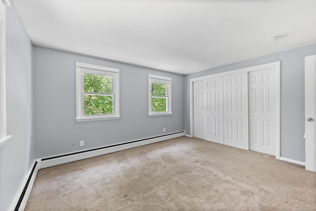 unfurnished bedroom featuring a baseboard heating unit, a baseboard radiator, carpet flooring, a closet, and baseboards