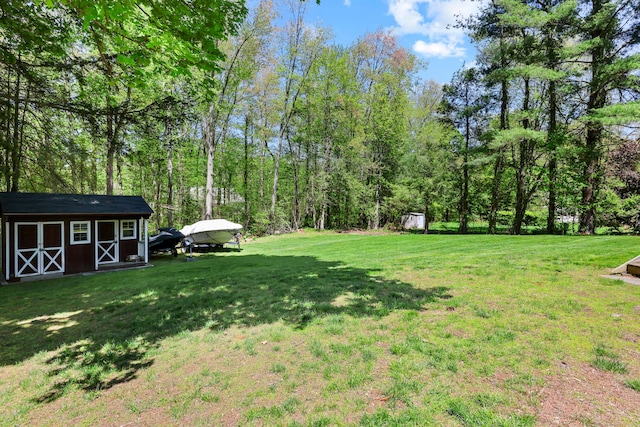 view of grassy yard featuring a storage shed, an outbuilding, and a detached carport