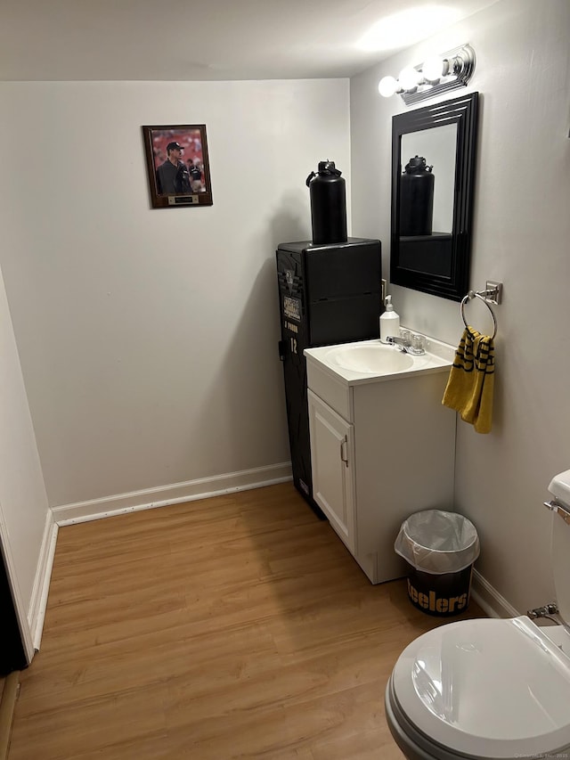 bathroom with wood finished floors, toilet, baseboards, and vanity