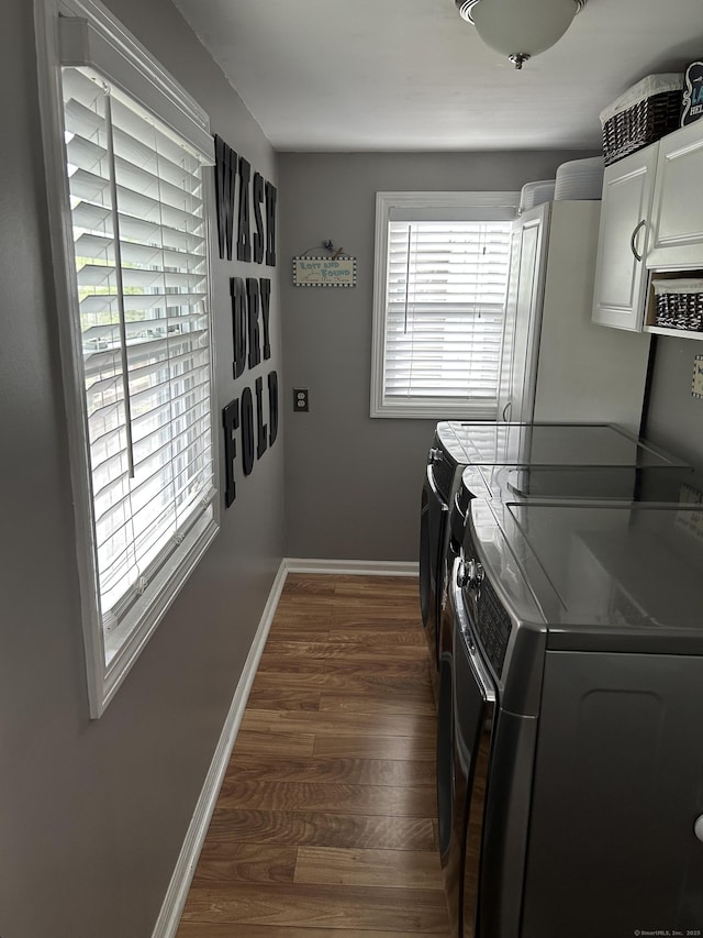 laundry area with washer and clothes dryer, cabinet space, dark wood finished floors, and baseboards
