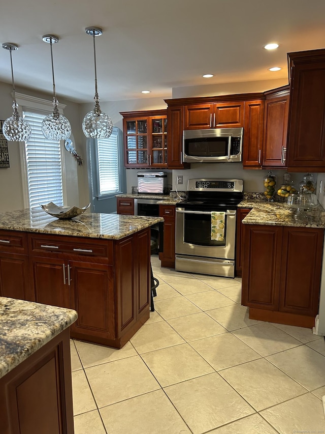kitchen with stainless steel appliances, light tile patterned floors, hanging light fixtures, glass insert cabinets, and stone counters