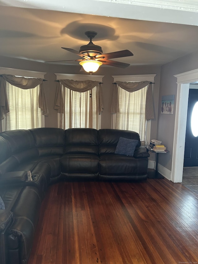 living area with wood-type flooring, a ceiling fan, and baseboards
