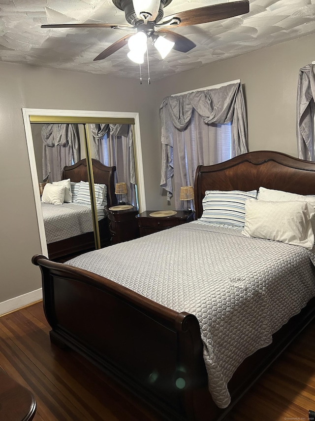 bedroom with baseboards, a closet, wood finished floors, and a ceiling fan